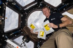 Tim Peake with packets of seeds from Tozer Seeds floating in space